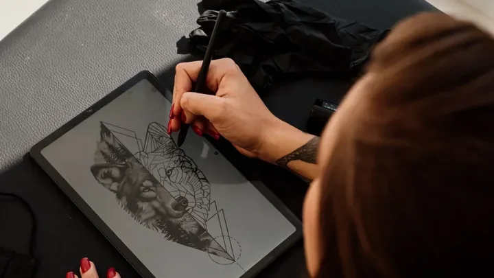 Artist drawing a geometric character illustration on a digital tablet