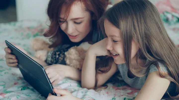 A mother and daughter looking at a tablet together at home